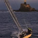 A yacht heading toward a rock with a light on