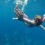 girl under the water with a snorkel on a yacht charter in greece