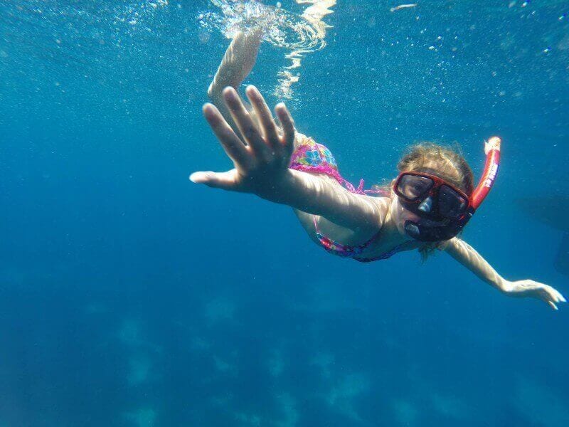 girl under the water with a snorkel on a yacht charter in greece